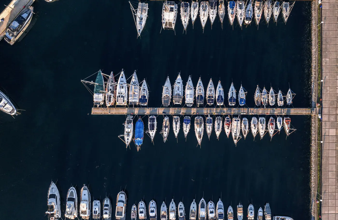 A marina from above: pontoons lined with sailboats and motorboats.